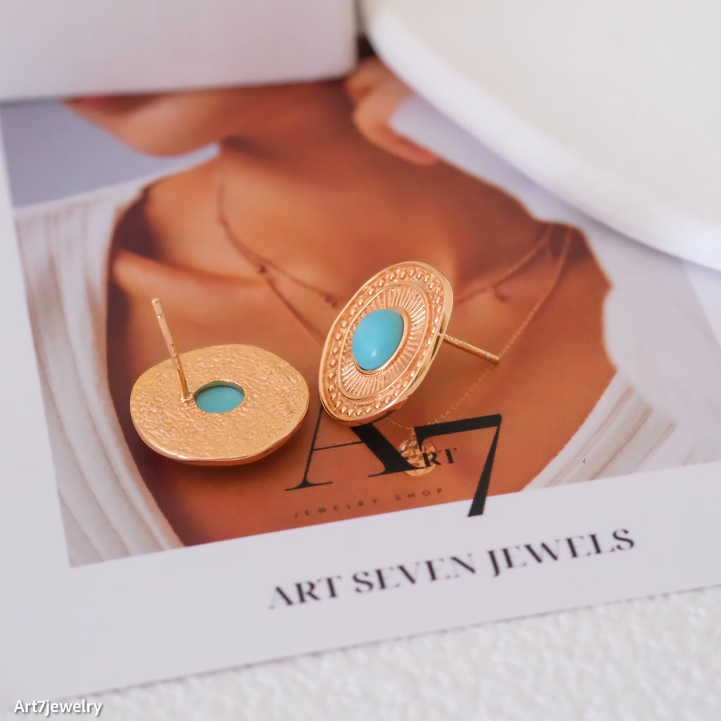 Gold earrings with turquoise stones on a magazine page with 'Art Seven Jewels' branding.