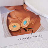 Gold earrings with turquoise stones on a magazine page with 'Art Seven Jewels' branding.