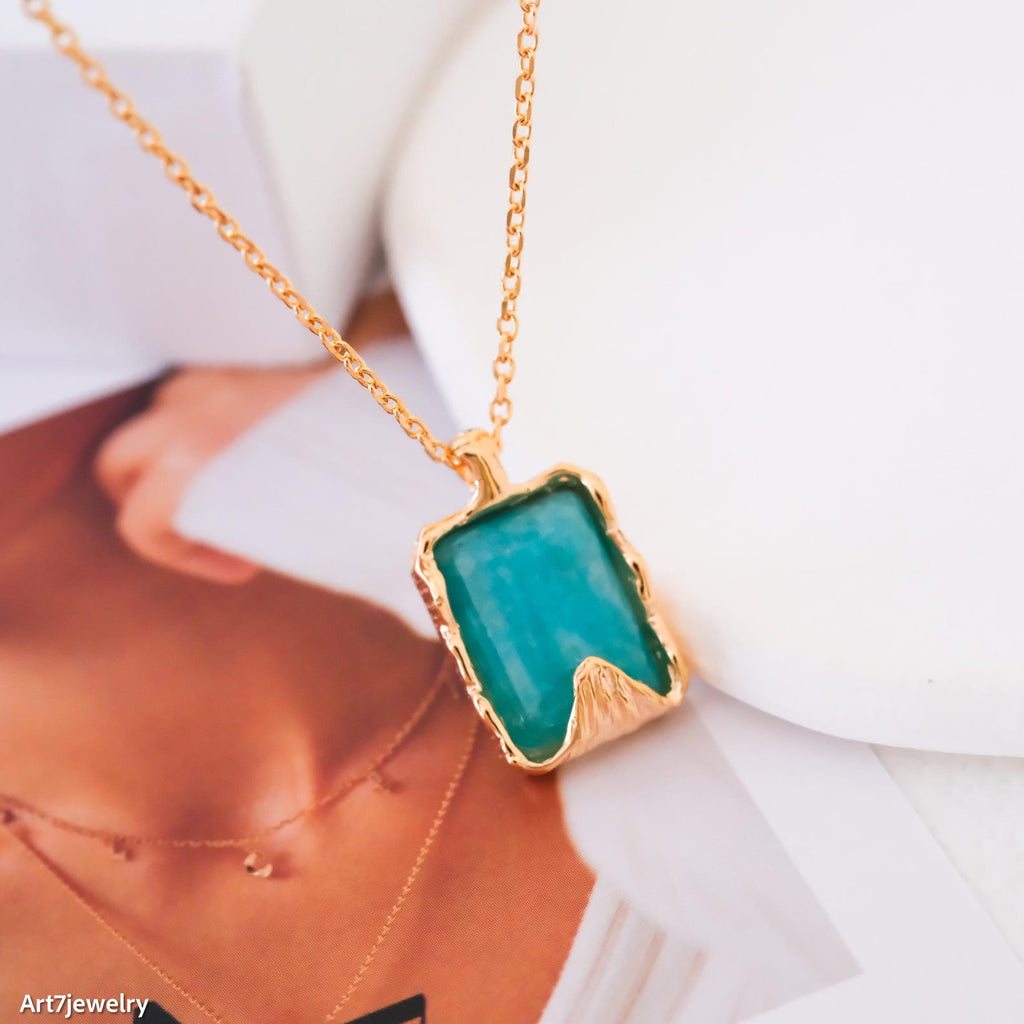 Gold amazonite necklace with a green pendant on a blurred background