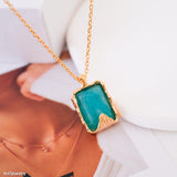 Gold amazonite necklace with a green pendant on a blurred background
