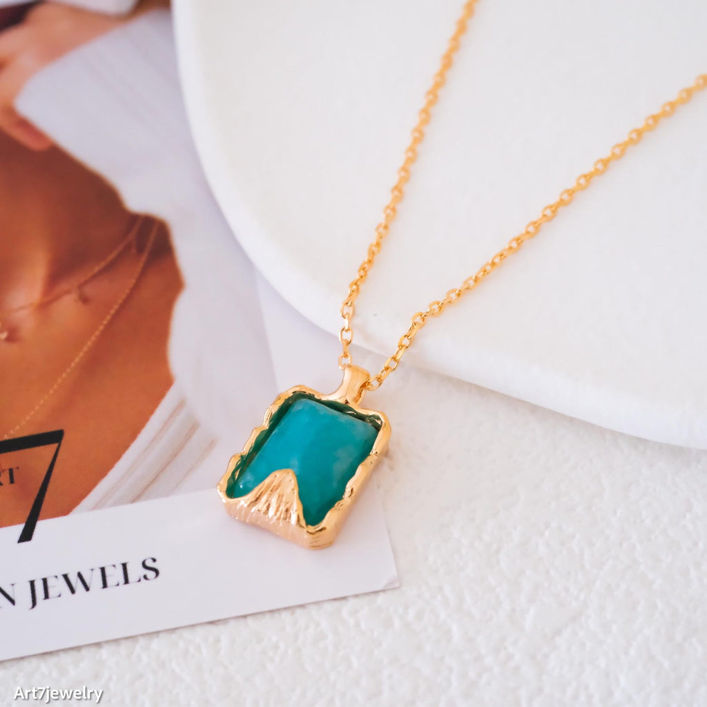 Gold necklace with a green pendant on a magazine background