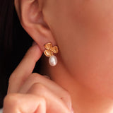 Gold earring with a pearl on an ear, close-up