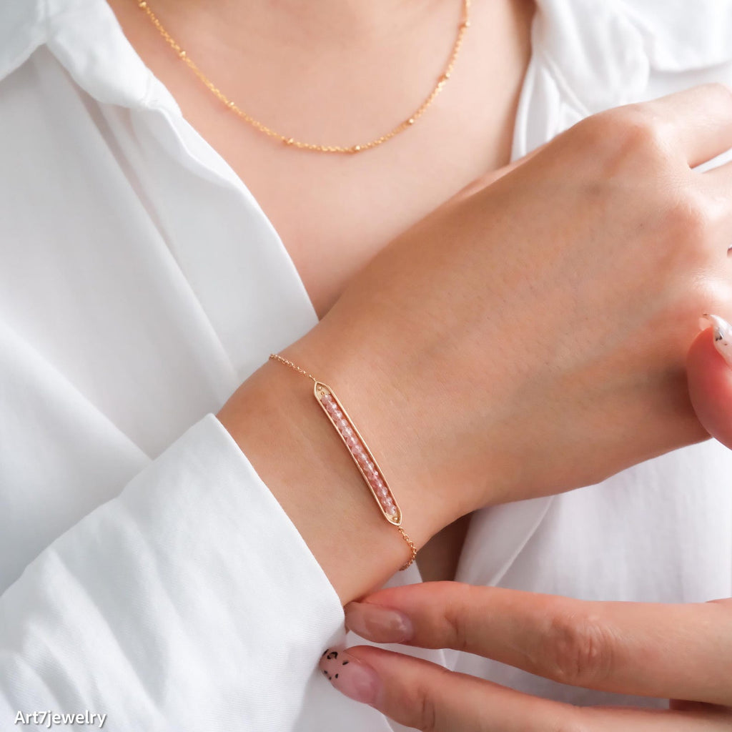 Rose gold bracelet on a wrist with a white shirt background