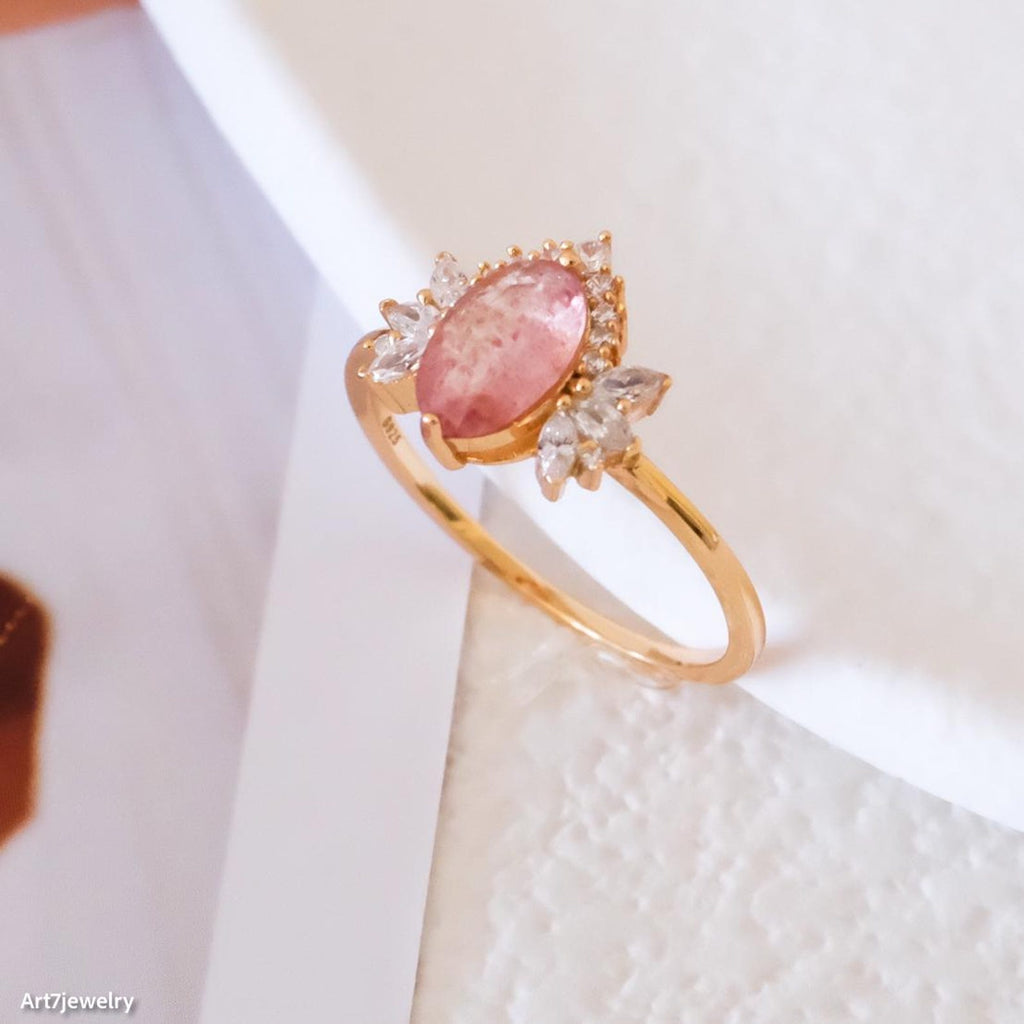 Gold ring with a pink stone on a white background