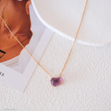 Necklace with a purple gemstone on a textured white surface