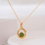 Gold necklace with a green pendant on a white background