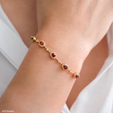 Natural garnet tennis bracelet featuring genuine deep red garnet gemstones surrounded by sparkling halo accents, set in a delicate gold bracelet design, elegant January birthstone jewelry and timeless gemstone gift for women.