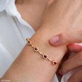 Natural garnet tennis bracelet featuring genuine deep red garnet gemstones surrounded by sparkling halo accents, set in a delicate gold bracelet design, elegant January birthstone jewelry and timeless gemstone gift for women.