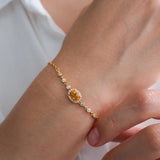 Natural citrine bracelet featuring a genuine golden yellow citrine gemstone surrounded by a sparkling halo, set on a delicate gold chain with bezel accents, elegant November birthstone jewelry for women.
