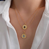 Gold sapphire pendant necklace with natural blue sapphire center stone, surrounded by small sparkling accents on a textured round gold disc, delicate minimalist chain jewelry for women
