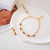 Natural garnet tennis bracelet featuring genuine deep red garnet gemstones surrounded by sparkling halo accents, set in a delicate gold bracelet design, elegant January birthstone jewelry and timeless gemstone gift for women.
