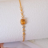 Natural citrine bracelet featuring a genuine golden yellow citrine gemstone surrounded by a sparkling halo, set on a delicate gold chain with bezel accents, elegant November birthstone jewelry for women.