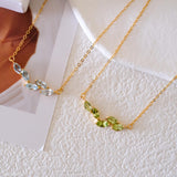 Natural peridot necklace featuring five genuine marquise-cut green peridot gemstones in a delicate curved gold bar design on a fine gold chain, elegant August birthstone jewelry for women.