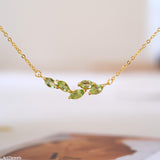 Natural peridot necklace featuring five genuine marquise-cut green peridot gemstones in a delicate curved gold bar design on a fine gold chain, elegant August birthstone jewelry for women.