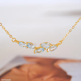 Natural aquamarine necklace featuring five genuine marquise-cut aquamarine gemstones in a delicate curved gold bar design on a fine gold chain, elegant March birthstone jewelry for women.