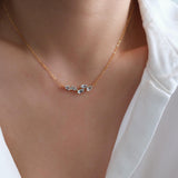 Natural aquamarine necklace featuring five genuine marquise-cut aquamarine gemstones in a delicate curved gold bar design on a fine gold chain, elegant March birthstone jewelry for women.