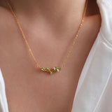 Natural peridot necklace featuring five genuine marquise-cut green peridot gemstones in a delicate curved gold bar design on a fine gold chain, elegant August birthstone jewelry for women.