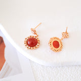 Natural carnelian dangle earrings with polished red carnelian cabochons, gold-tone filigree settings, and clear crystal accents.