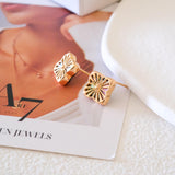 Clover shell stud earrings with iridescent natural shell inlays and gold-tone openwork radiating line details.