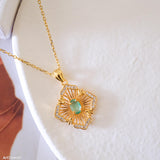 Natural emerald clover pendant necklace with a green emerald center, gold-tone openwork radiating lines, and clear crystal accents.