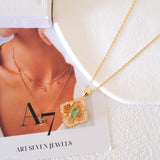 Natural emerald clover pendant necklace with a green emerald center, gold-tone openwork radiating lines, and clear crystal accents.