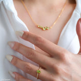 Oval green peridot solitaire ring in a gold-tone four-prong setting with sparkling clear stone band accents.