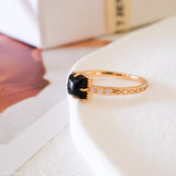 Square black onyx ring in a detailed gold-tone setting with sparkling clear stone accents along the band.