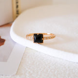 Square black onyx ring in a detailed gold-tone setting with sparkling clear stone accents along the band.