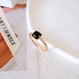 Square black onyx ring in a detailed gold-tone setting with sparkling clear stone accents along the band.