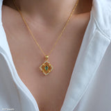 Natural emerald clover pendant necklace with a green emerald center, gold-tone openwork radiating lines, and clear crystal accents.