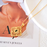 Natural emerald clover pendant necklace with a green emerald center, gold-tone openwork radiating lines, and clear crystal accents.