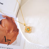Natural emerald clover pendant necklace with a green emerald center, gold-tone openwork radiating lines, and clear crystal accents.