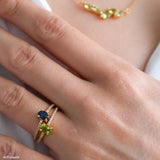 Oval green peridot solitaire ring in a gold-tone four-prong setting with sparkling clear stone band accents.
