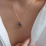 Close up of blue gemstone with gold filigree crown setting and pave crystals