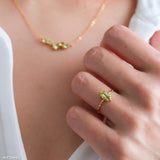 Olive-green marquise peridot ring in a gold-tone prong setting with a delicate wave-style band.