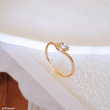Pear-cut light blue aquamarine wave ring in a gold-tone setting with a delicate clear stone accent.