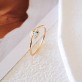 Pear-cut light blue aquamarine wave ring in a gold-tone setting with a delicate clear stone accent.