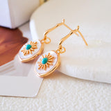 Gold-tone turquoise drop earrings with iridescent mother of pearl discs and detailed sunburst center accents.