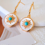 Gold-tone turquoise drop earrings with iridescent mother of pearl discs and detailed sunburst center accents.