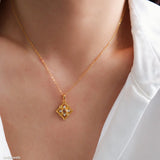 Gold-tone citrine clover pendant necklace with a faceted yellow center stone and sparkling clear stone accents.