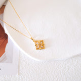 Gold-tone citrine clover pendant necklace with a faceted yellow center stone and sparkling clear stone accents.