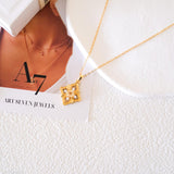 Gold-tone citrine clover pendant necklace with a faceted yellow center stone and sparkling clear stone accents.