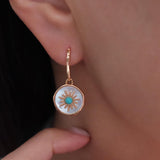 Gold-tone turquoise drop earrings with iridescent mother of pearl discs and detailed sunburst center accents.