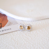 Citrine sunflower stud earrings with golden-yellow center stones and clear baguette-cut halo accents.