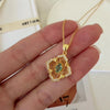 Natural emerald clover pendant necklace with a green emerald center, gold-tone openwork radiating lines, and clear crystal accents.