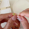 Oval green peridot solitaire ring in a gold-tone four-prong setting with sparkling clear stone band accents.