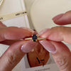 Blue sapphire solitaire ring with an oval deep-blue center stone, gold-tone four-prong setting, and sparkling clear stone band accents.