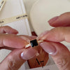 Square black onyx ring in a detailed gold-tone setting with sparkling clear stone accents along the band.