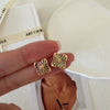 Clover shell stud earrings with iridescent natural shell inlays and gold-tone openwork radiating line details.