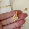 Gold-tone citrine clover pendant necklace with a faceted yellow center stone and sparkling clear stone accents.